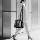 A stylish MOOV Motion work bag featuring dual handles and a long shoulder strap, enhancing her sophisticated and elegant appearance. The Motion stands out as a key accessory for busy professionals, combining functionality with a chic design.